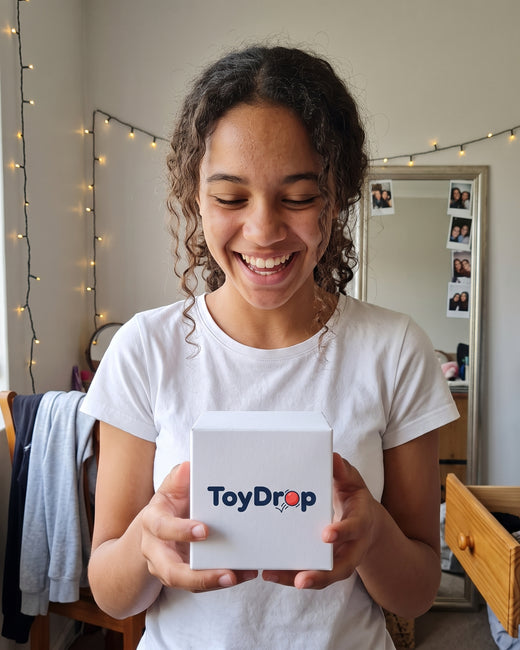 Smiling girl in her bedroom holding a white ToyDrop box