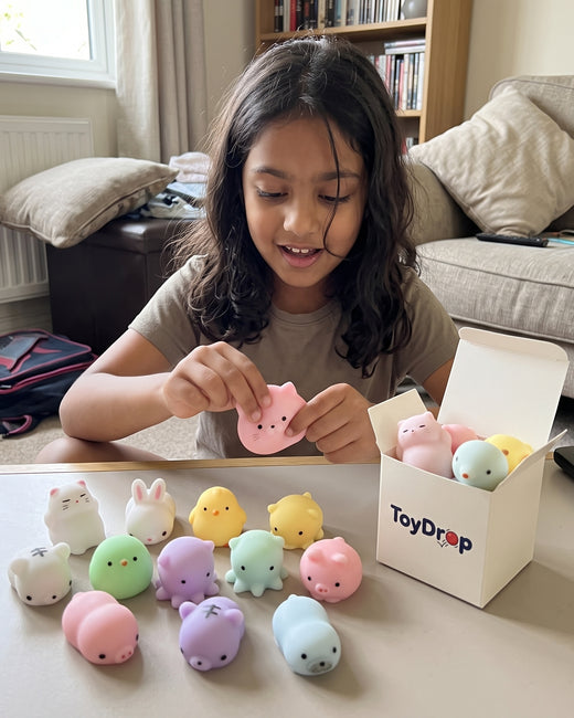 Girl lining up mini squishy animals on a table next to an open ToyDrop box